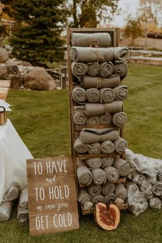 a stack of folded towels sitting on top of a grass covered field next to a wooden sign