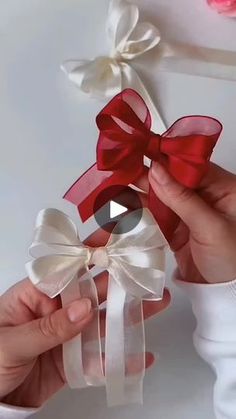 two hands are holding red and white bows