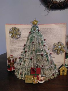 a christmas tree made out of books on top of a wooden table next to an open book