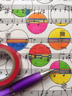 a pair of scissors and tape sitting on top of music sheets with colorful circles in the background