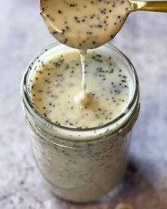 a spoon with some kind of liquid in it on top of a jar filled with something