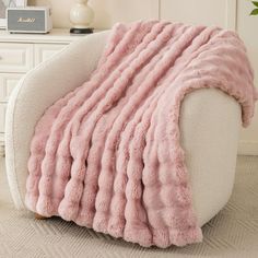 a white chair with a pink fluffy blanket on it's back and the seat up