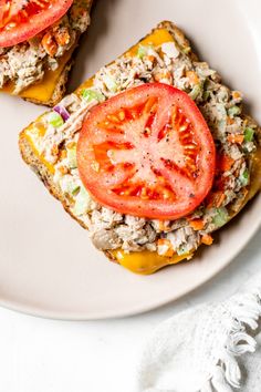 two pieces of toast with cheese, tomatoes and other toppings on it sitting on a white plate