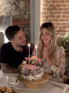 a man and woman sitting at a table with a birthday cake in front of them