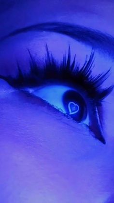 a woman's eye with long eyelashes and blue light shining through the iris area