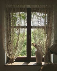 a vase sitting on top of a window sill in front of a curtained window