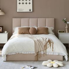 a bedroom with a bed, nightstands and pictures on the wall above it in neutral colors