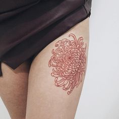 a woman's thigh with a red flower tattoo on the lower part of her leg