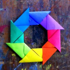 an origami wreath made out of colored paper on top of a wooden surface