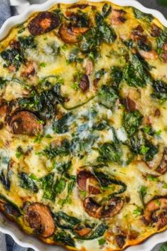 a quiche with spinach, mushrooms and cheese in a white dish on a table