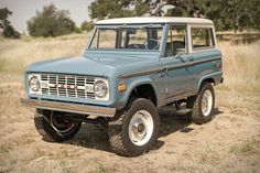 an old ford bronco is parked in the dirt