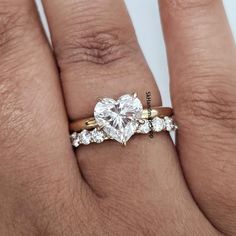 a woman's hand with a gold and white engagement ring on top of her finger