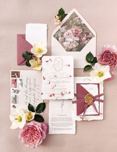 the wedding stationery is laid out on top of each other, with pink and white flowers