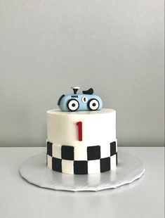 a white cake with black and white checkered design on it, topped with a blue car