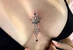 a woman with a tattoo on her stomach holding onto the side of her breast and looking down