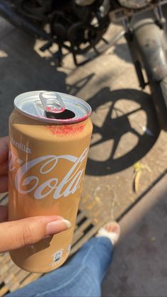 a person holding up a can of coca cola