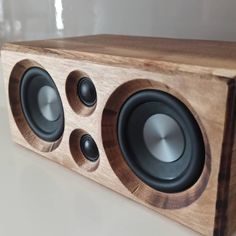 a close up of a wooden speaker on a white surface with glass in the background