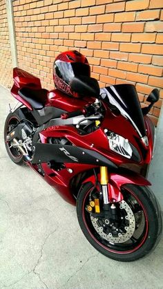 a red motorcycle parked next to a brick wall