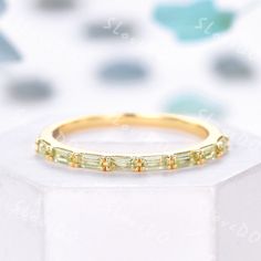 a yellow gold ring with three baguettes set in the middle on top of a white box