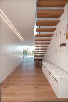 an empty hallway with wooden floors and white walls, leading up to the upper floor