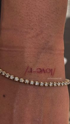 a woman's arm with a gold bracelet on it and the word love written in red ink