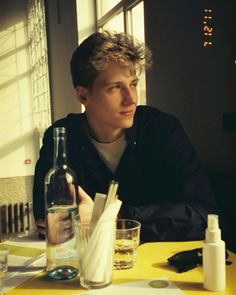 a young man sitting at a table in front of a bottle