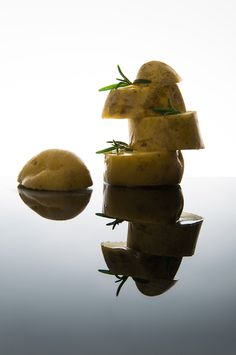 potatoes are stacked on top of each other in front of a white background with reflection