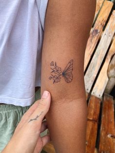 a person with a butterfly tattoo on their arm next to another person's arm