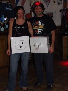 a man and woman standing next to each other holding boxes with electrical plugs in them