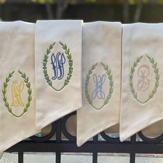 four monogrammed towels hanging on a wrought iron fence