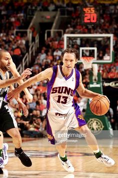 two basketball players in the middle of a game, one is dribbling the ball