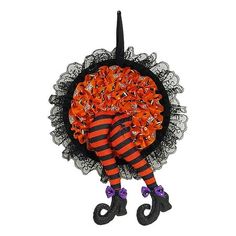 an orange and black halloween decoration hanging on a wall with legs in the shape of a pumpkin