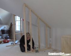 a woman kneeling down on the floor in front of an unfinished room that is being built