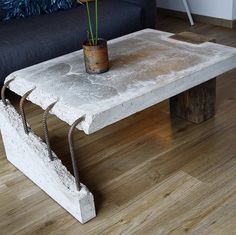 a concrete table with a potted plant on it and a black couch in the background