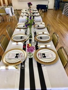 a long table set with place settings and flowers in vases on the top plates