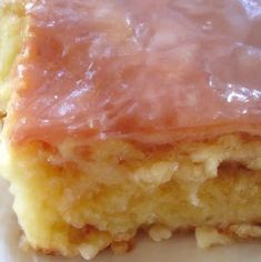 a piece of cake with pink icing sitting on top of a white plate next to a fork