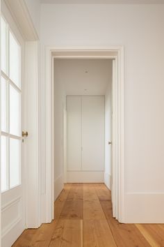 an empty room with white walls and wood flooring is seen from the doorway to the hallway