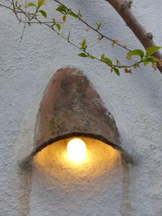 a light that is on in the side of a building next to a tree branch