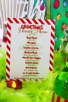 a menu for a christmas dinner on a table with green feathers and candles in front of it