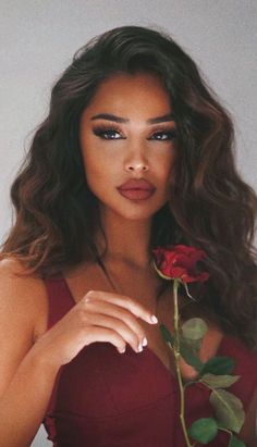 a woman in a red dress holding a rose with her right hand and looking at the camera