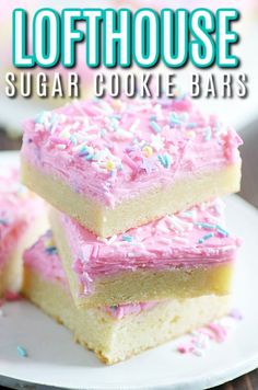 three sugar cookie bars with pink frosting and sprinkles stacked on top of each other