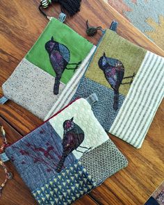 three pieces of fabric with birds on them sitting on a wooden table next to scissors and thread