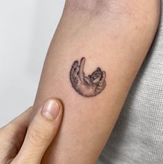 a person with a small tattoo on their arm holding a cat in the shape of a heart