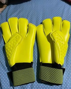 two yellow soccer gloves sitting on top of a blue bed covered in polka dot sheets