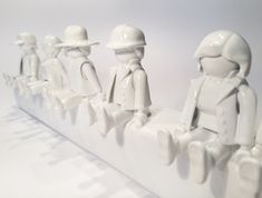 a group of lego figures sitting on top of a white wall next to each other