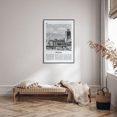 a bed with pillows and blankets on it in front of a wall hanging above the window