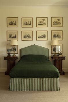 a bed with green bedspread in front of pictures on the wall above it