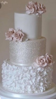 a three tiered white wedding cake with pink flowers on the top and bottom layer