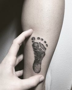 a person's foot with a black ink tattoo on their left arm and hand