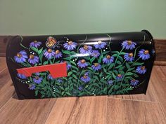 a black purse with purple flowers and a butterfly on the front, sitting on a wooden floor